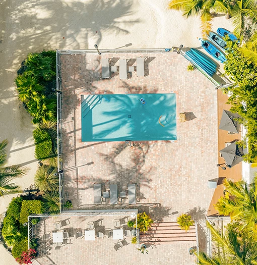 a pool on a brick patio with chairs and trees