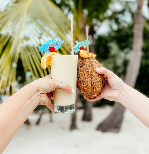 a hand holding a glass of milkshake and a coconut