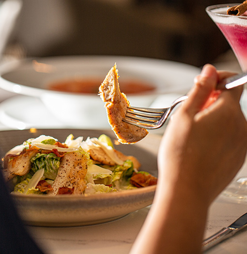 a person holding a fork over a salad