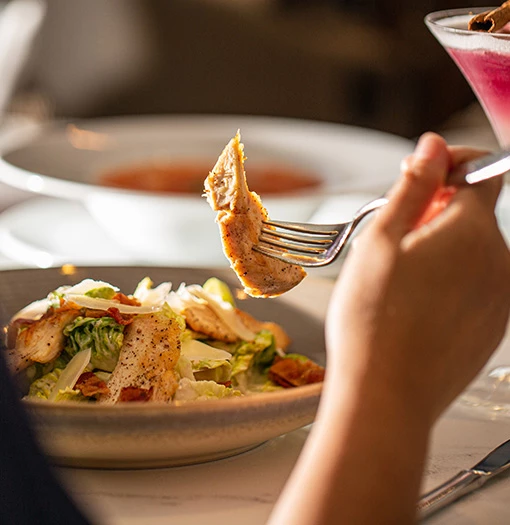 a person holding a fork over a salad