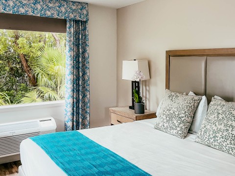 a bed with a blue blanket and a lamp next to a window