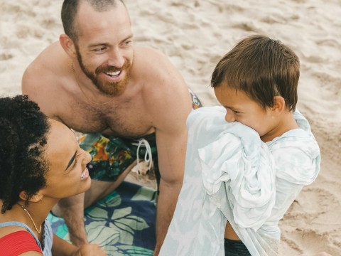 a man and woman sitting on a beach with a child