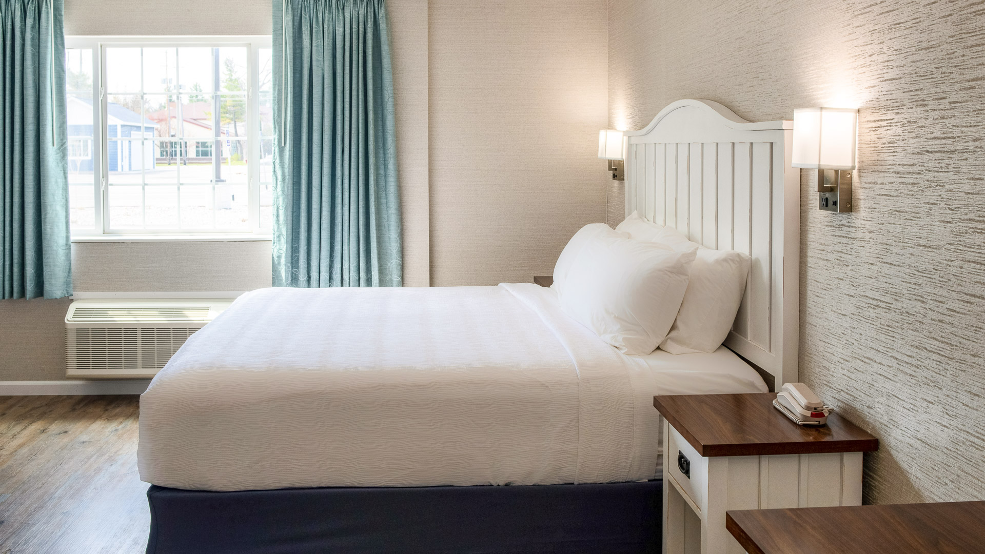 A hotel room with a bed, nightstand, and window