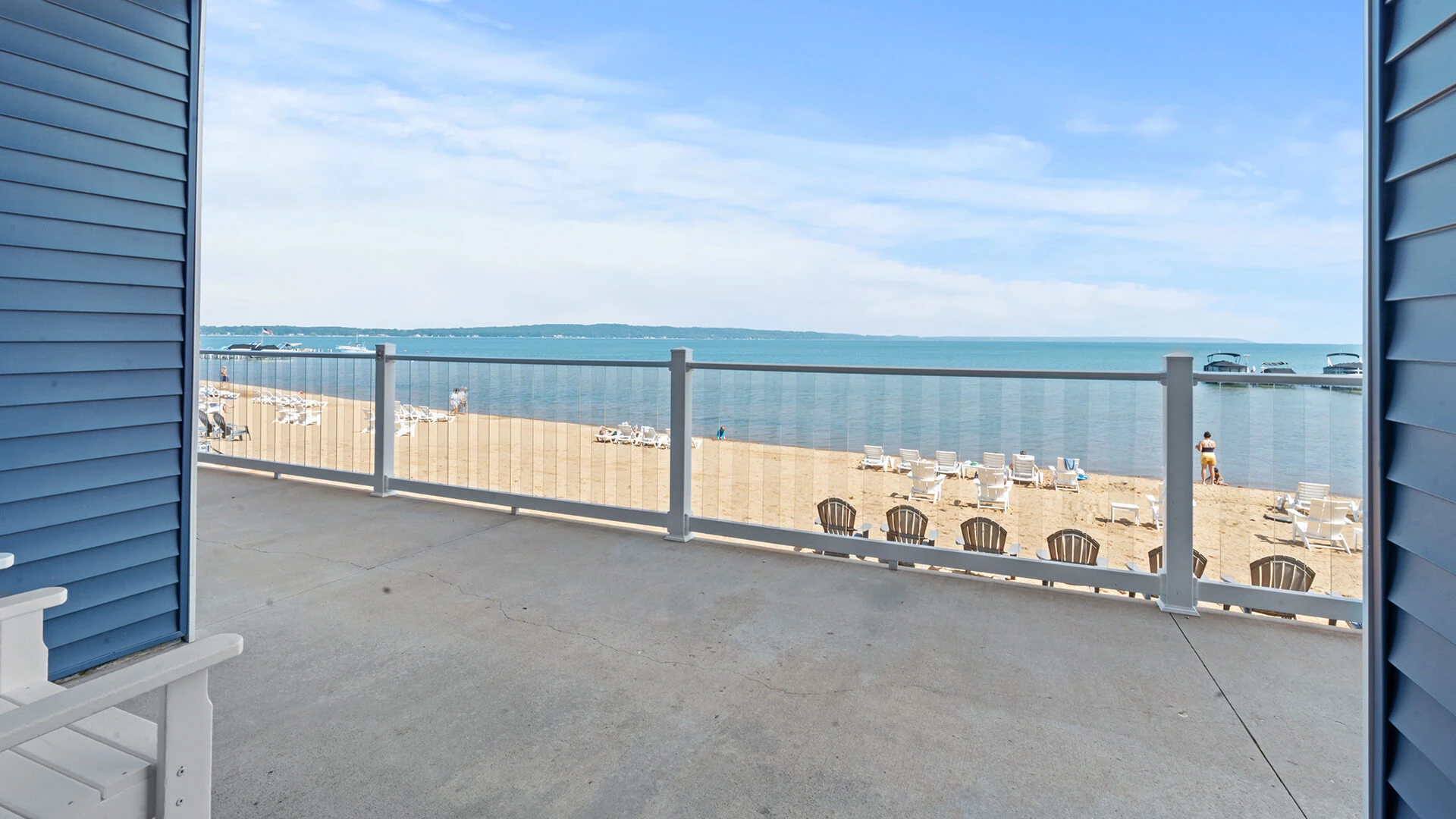 a deck with a fence and chairs on the beach