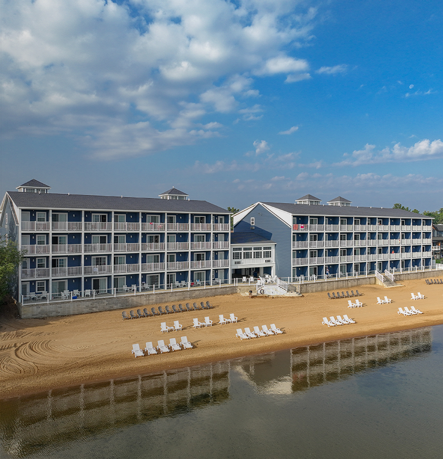 A large blue and white building with balconies and a beach in front of it.