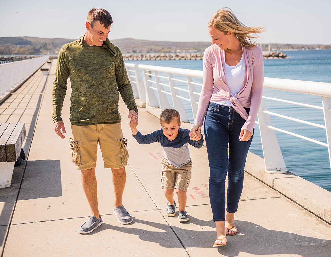 a man and woman holding hands and walking with a child