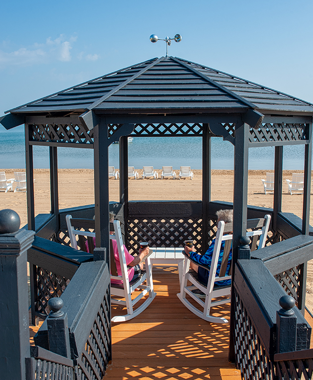 a gazebo with a couple of people sitting in chairs on a beach