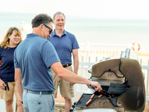 a group of people standing around a barbecue grill