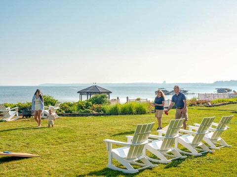 a group of people standing in a lawn with chairs on a sunny day
