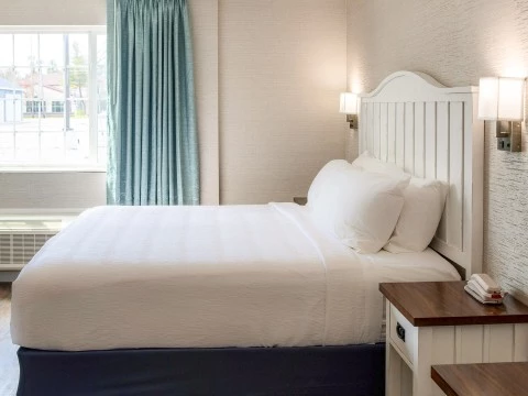 a bed with a white bedding and a blue curtain