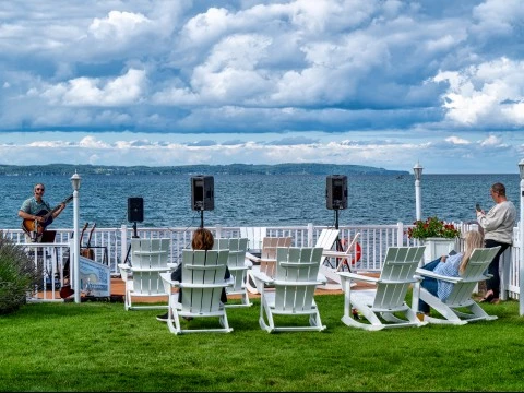 a group of people sitting in chairs on grass by a body of water
