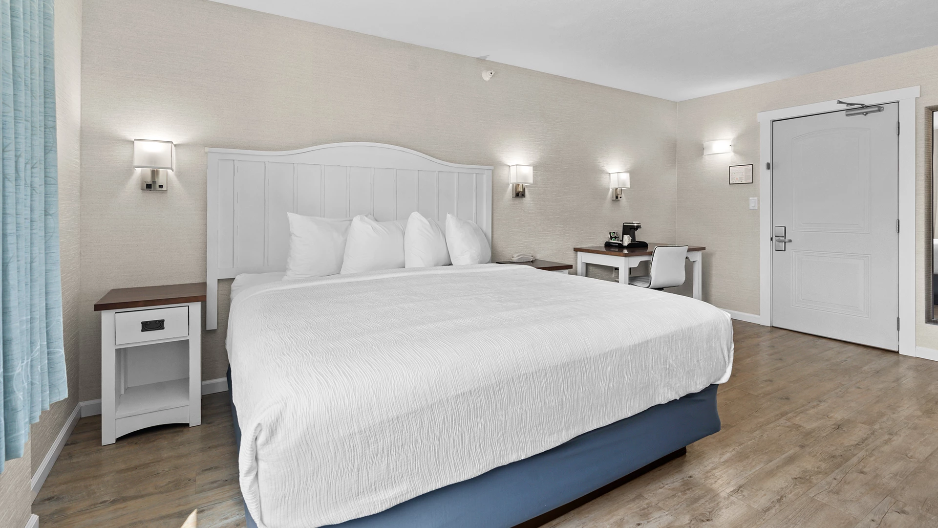 a bed with a white bedding and a desk