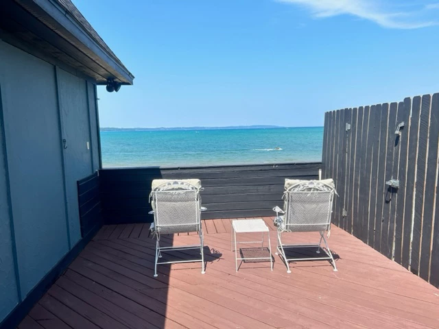a deck with chairs and a table overlooking the ocean