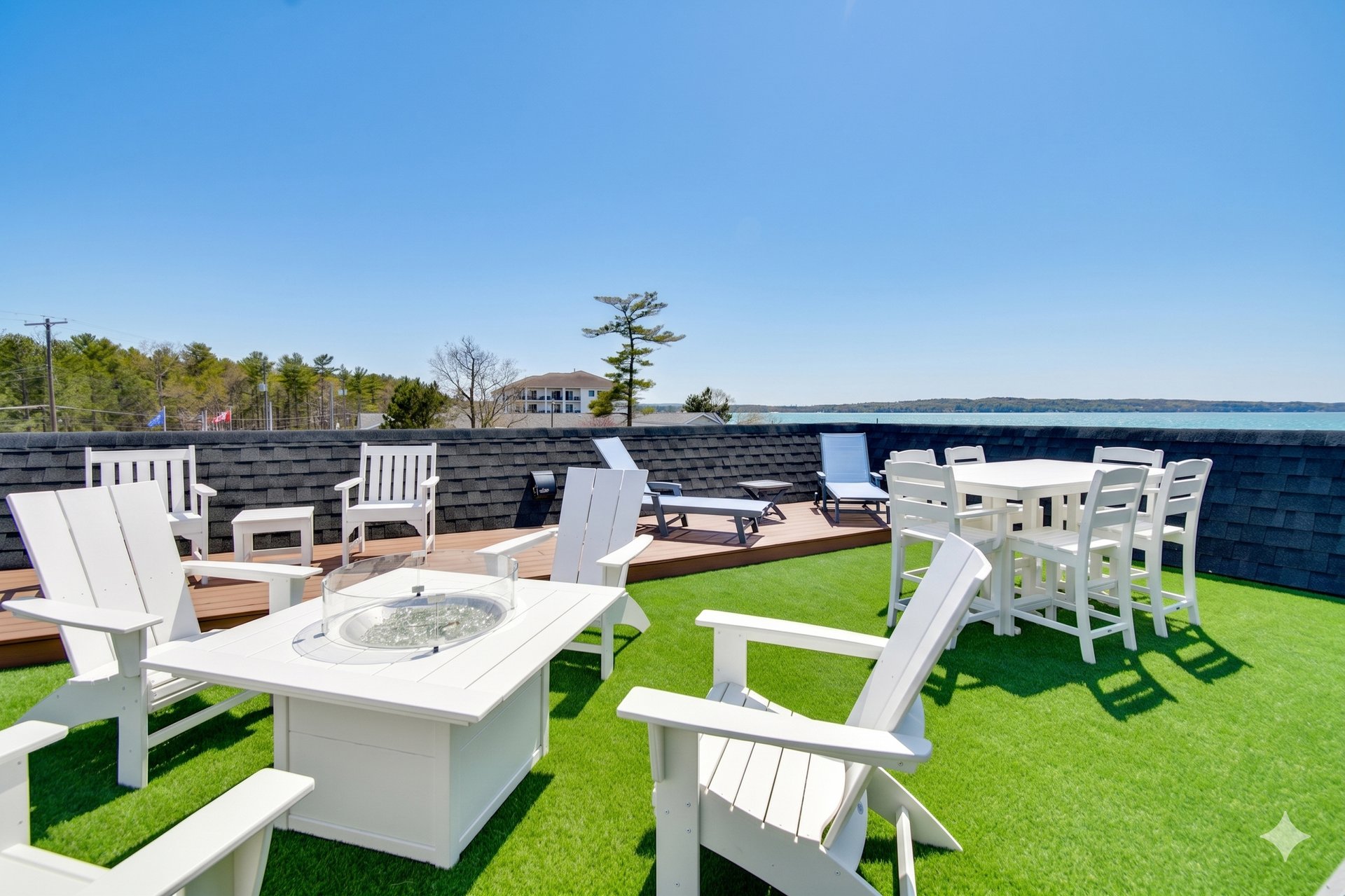 a patio with white furniture and chairs on a green lawn