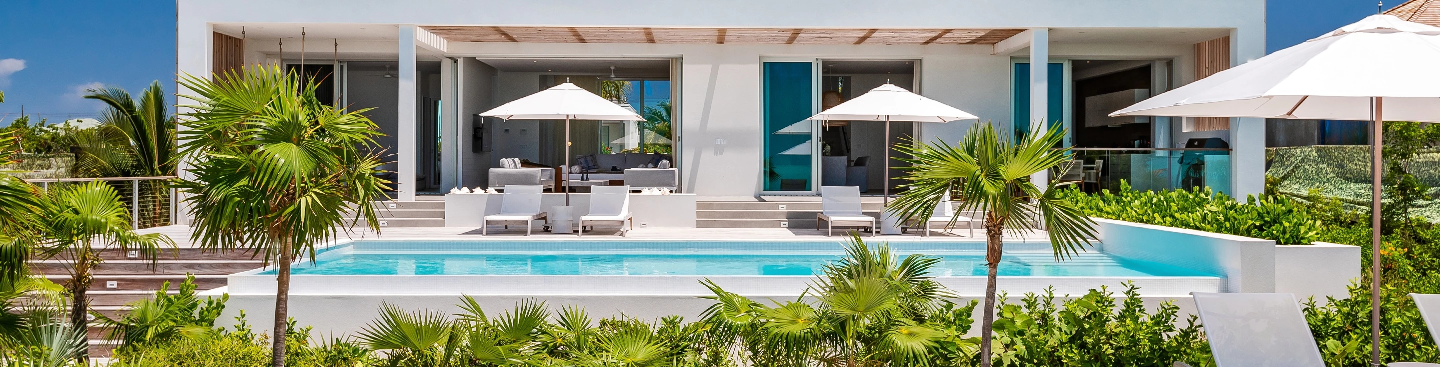 a pool with lounge chairs and umbrellas by a building
