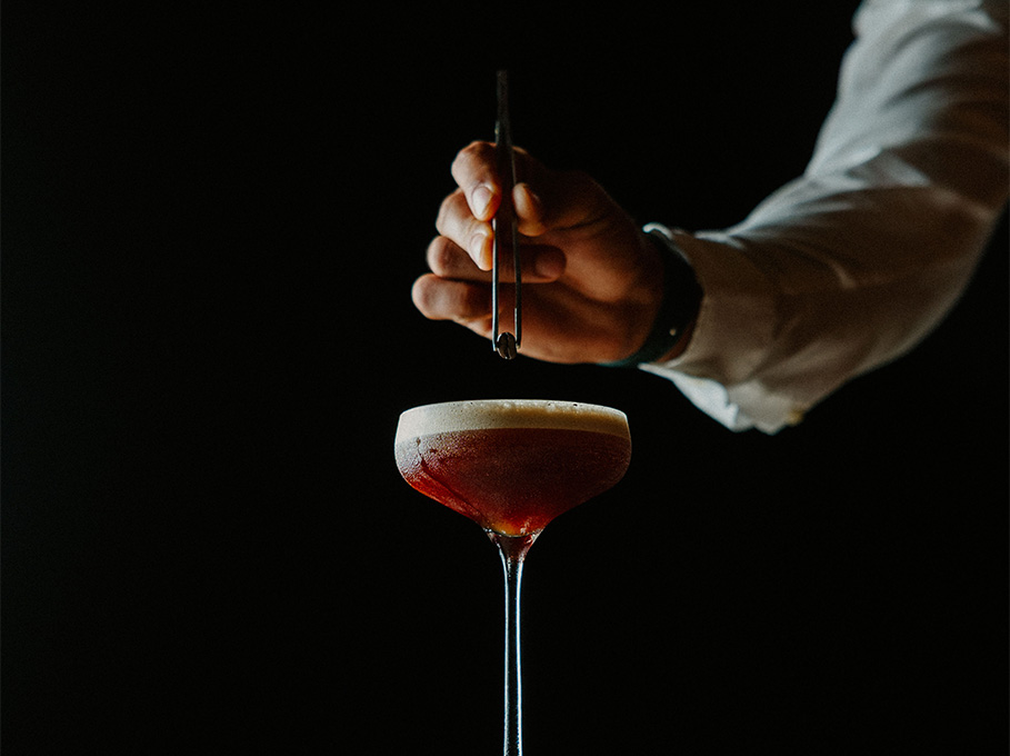 a person holding tweezers over a drink