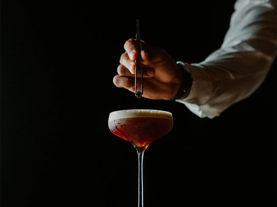 a person holding tweezers over a drink