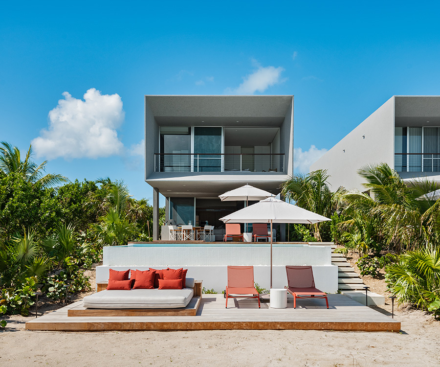 a beach house with lounge chairs and umbrellas