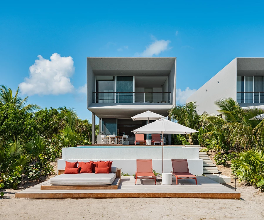 a beach house with lounge chairs and umbrellas