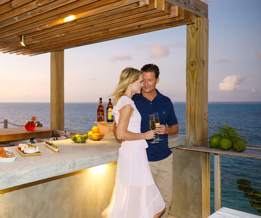 a man and woman standing next to each other and holding drinks