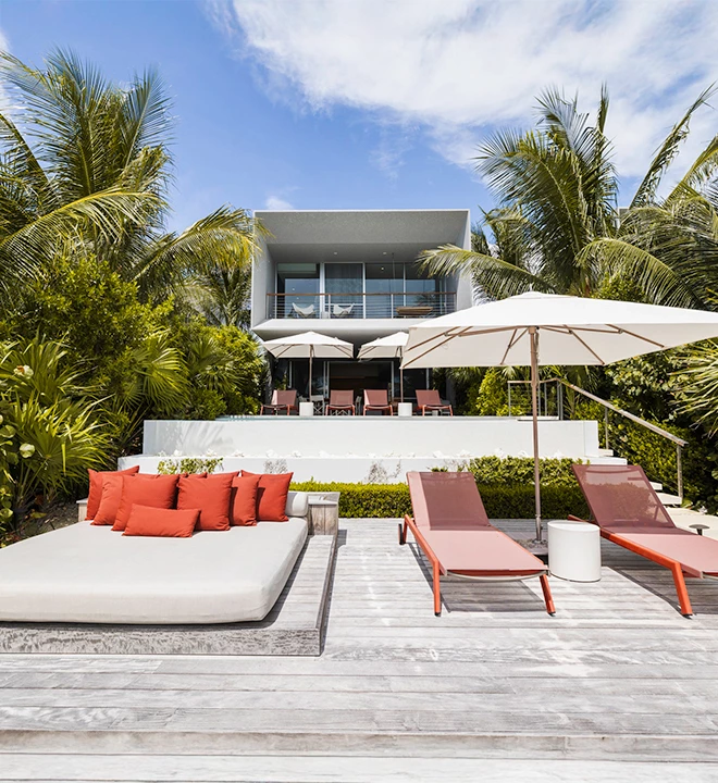 a deck with lounge chairs and umbrellas in front of a house