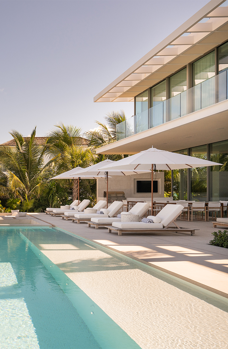 a pool with lounge chairs and umbrellas by a building