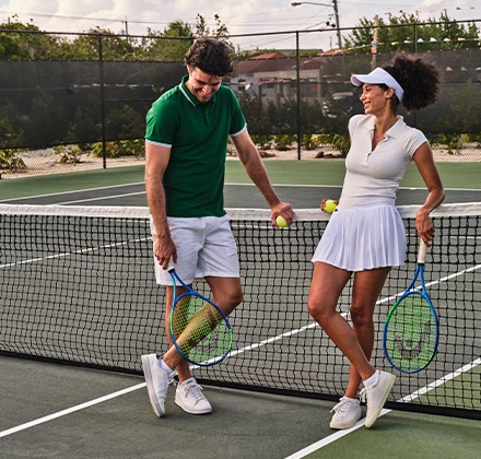 a man and woman holding tennis rackets on a tennis court