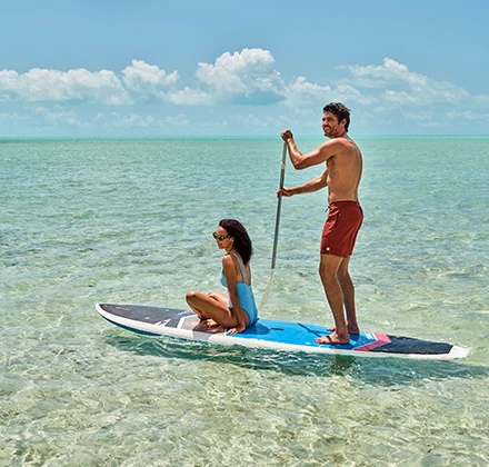 a man and woman on a surfboard in the water