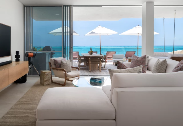 a living room with a large glass wall and a large table with umbrellas