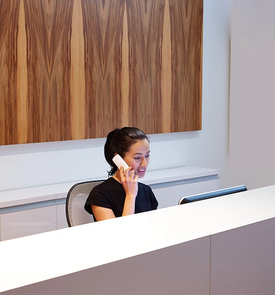 a woman sitting at a desk talking on the phone