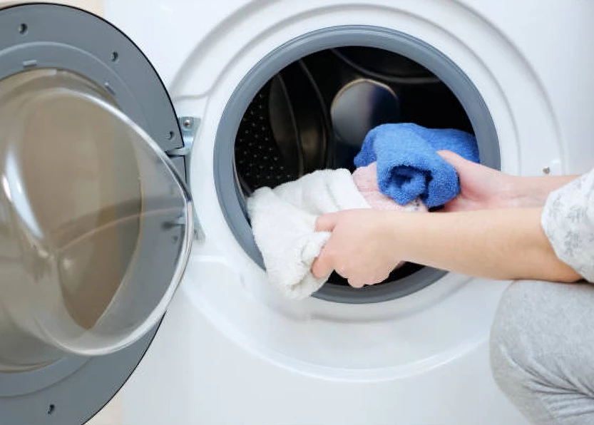 a person putting clothes into a washing machine