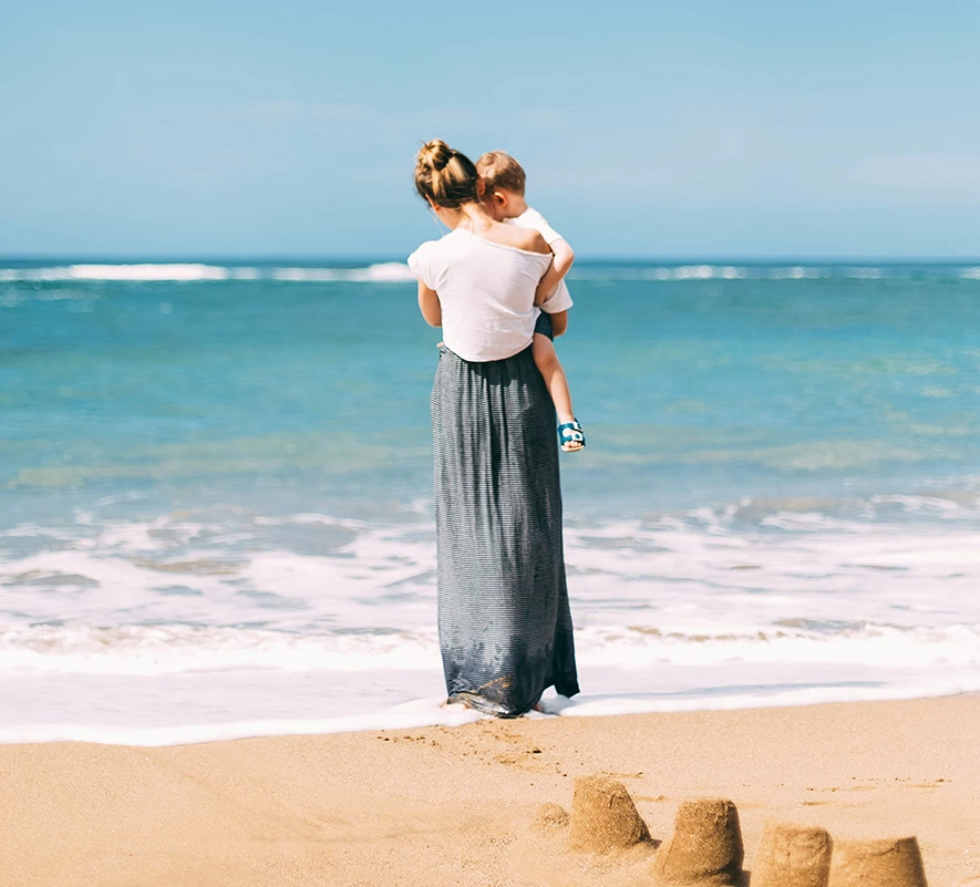 a woman holding a child on a beach
