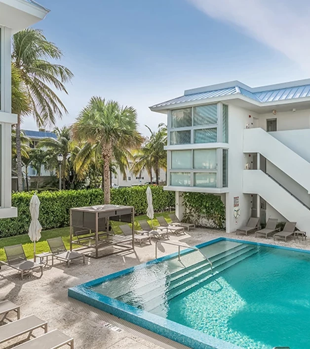 a swimming pool with chairs and a table in front of a building