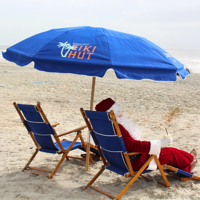 a man in a suit sitting under an umbrella on a beach