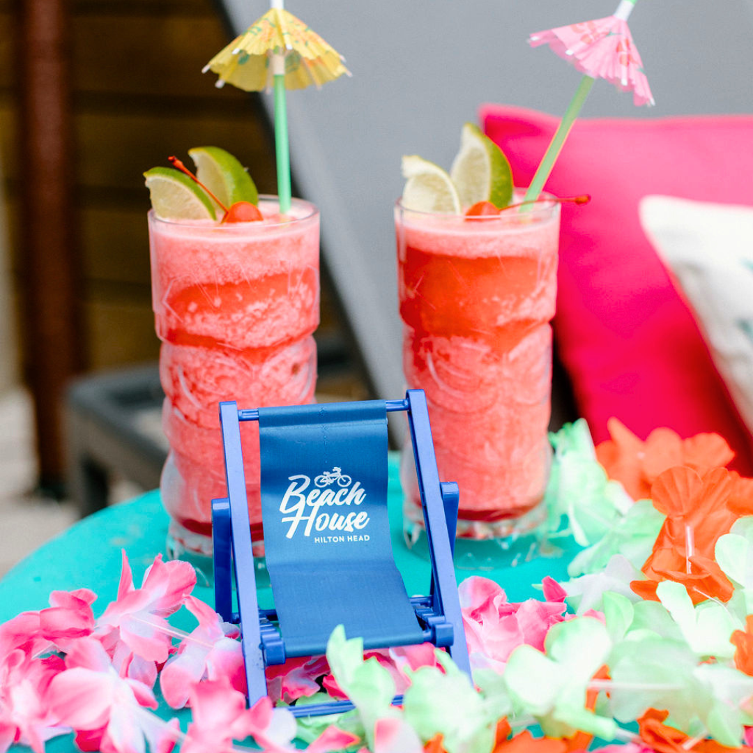 two drinks in glasses with straws and flowers