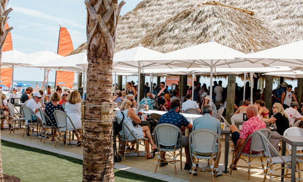 a group of people sitting at tables under umbrellas