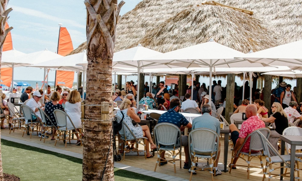 a group of people sitting at tables under umbrellas