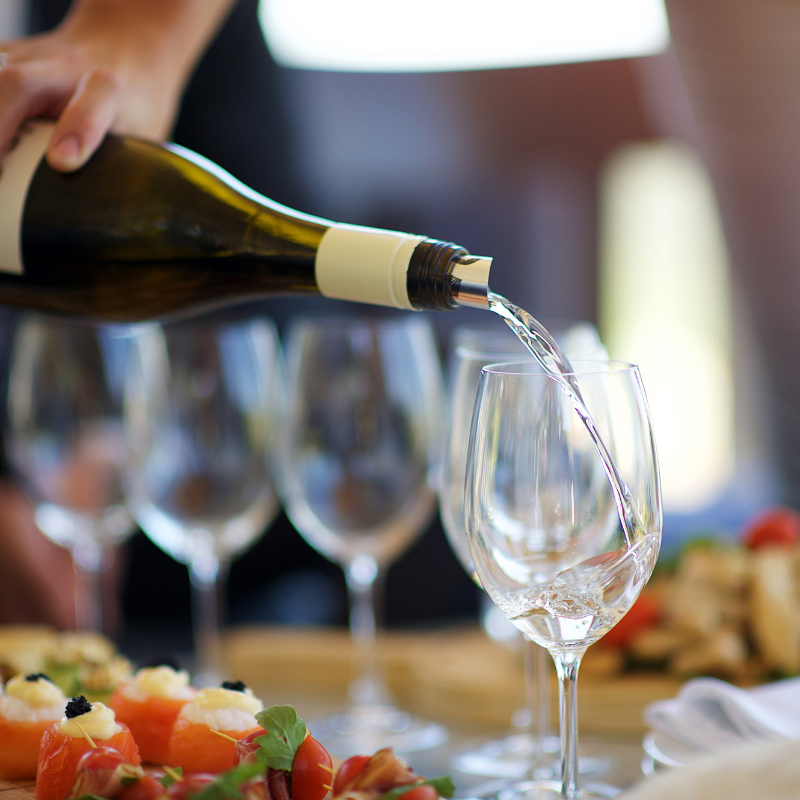 a person pouring wine into a glass