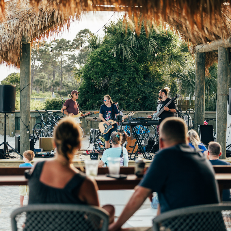 a group of people playing instruments under a straw covered gazebo
