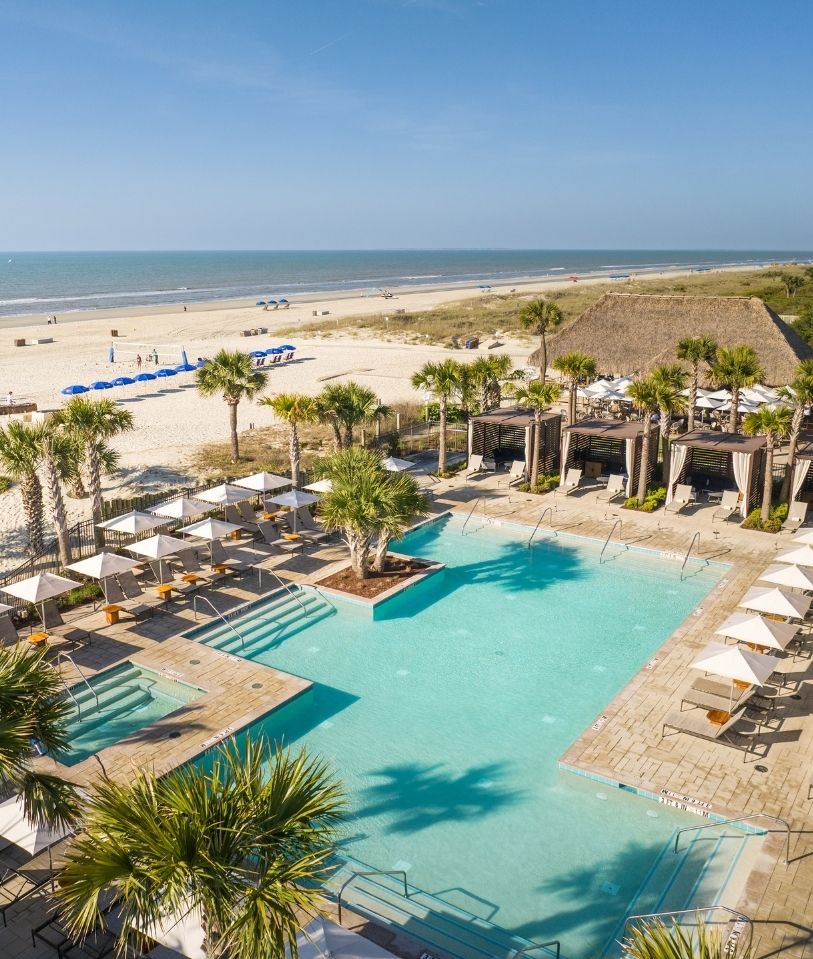 a swimming pool with umbrellas and palm trees on a beach