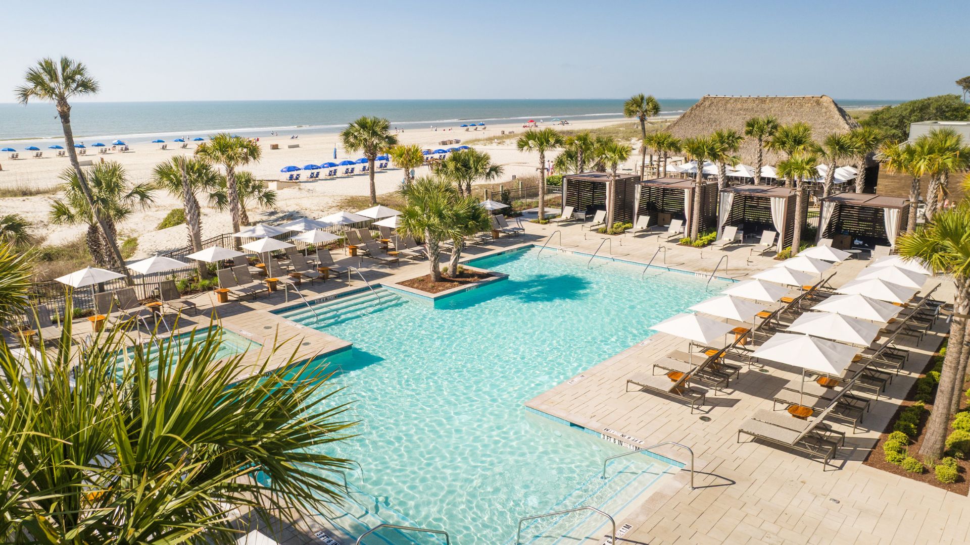 a swimming pool with umbrellas and chairs on a beach