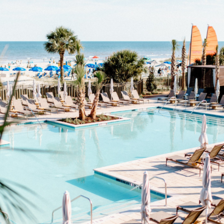 a pool with lounge chairs and umbrellas on a beach