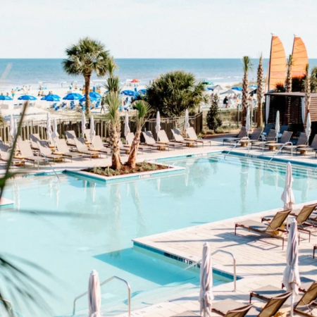 a pool with lounge chairs and umbrellas on a beach