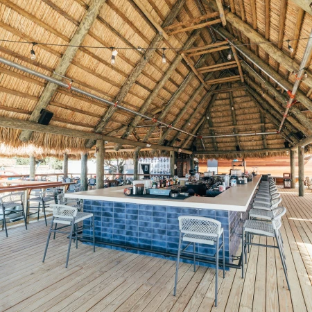 a bar with chairs and a thatched roof