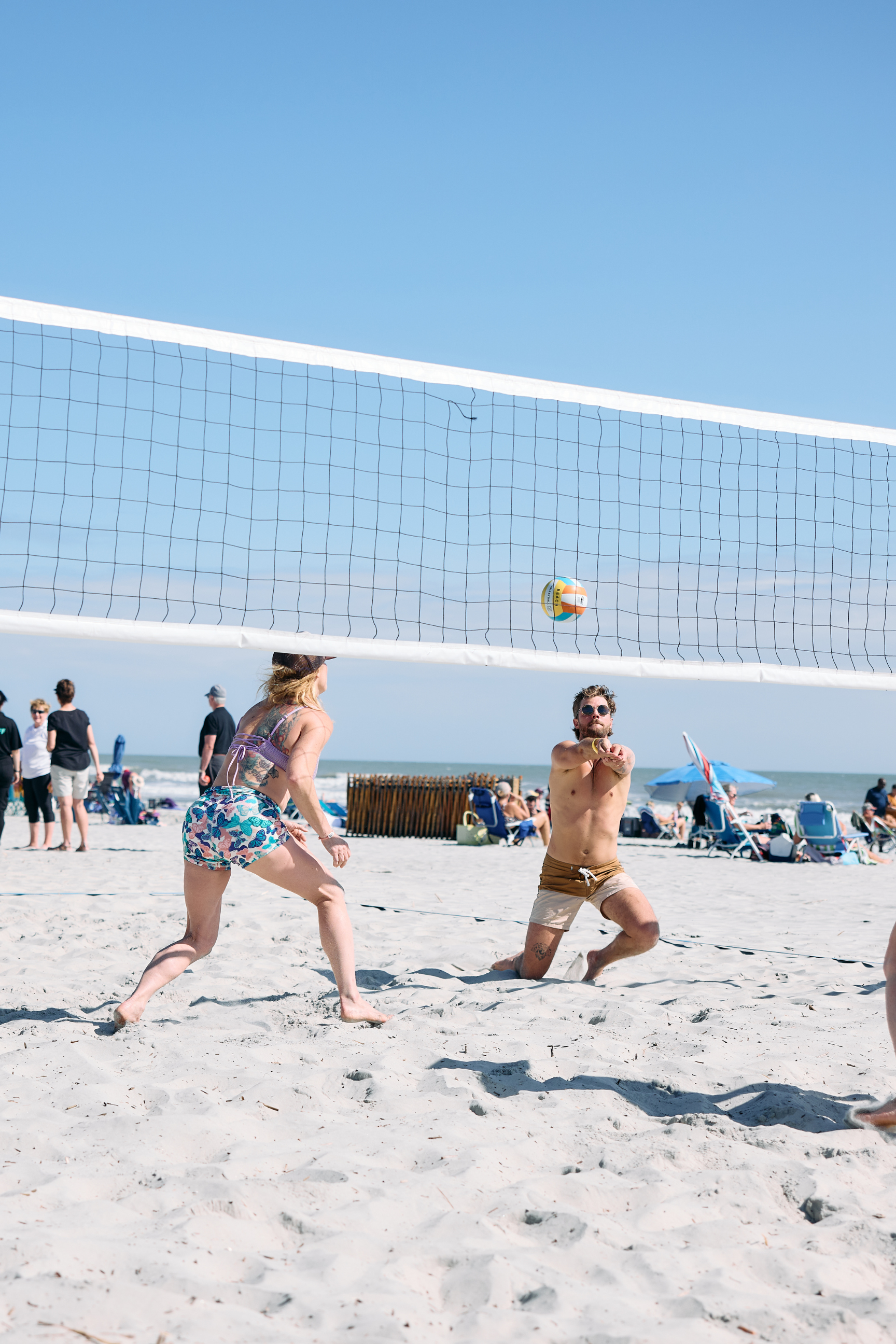 a group of people playing volleyball on a beach