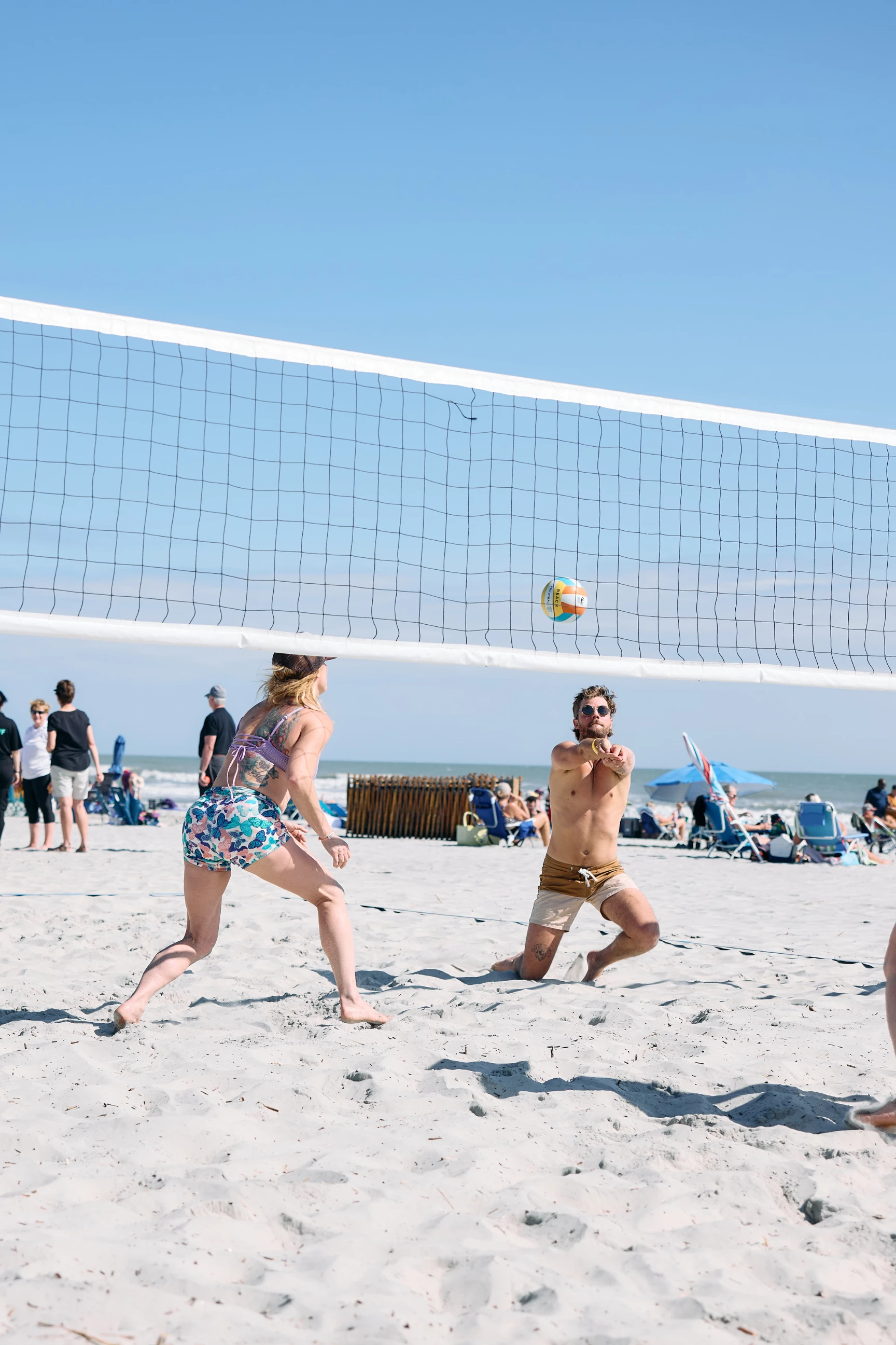 a group of people playing volleyball on a beach