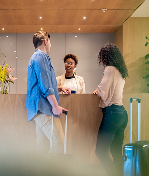 a receptionist talking to a man and a woman at the front desk