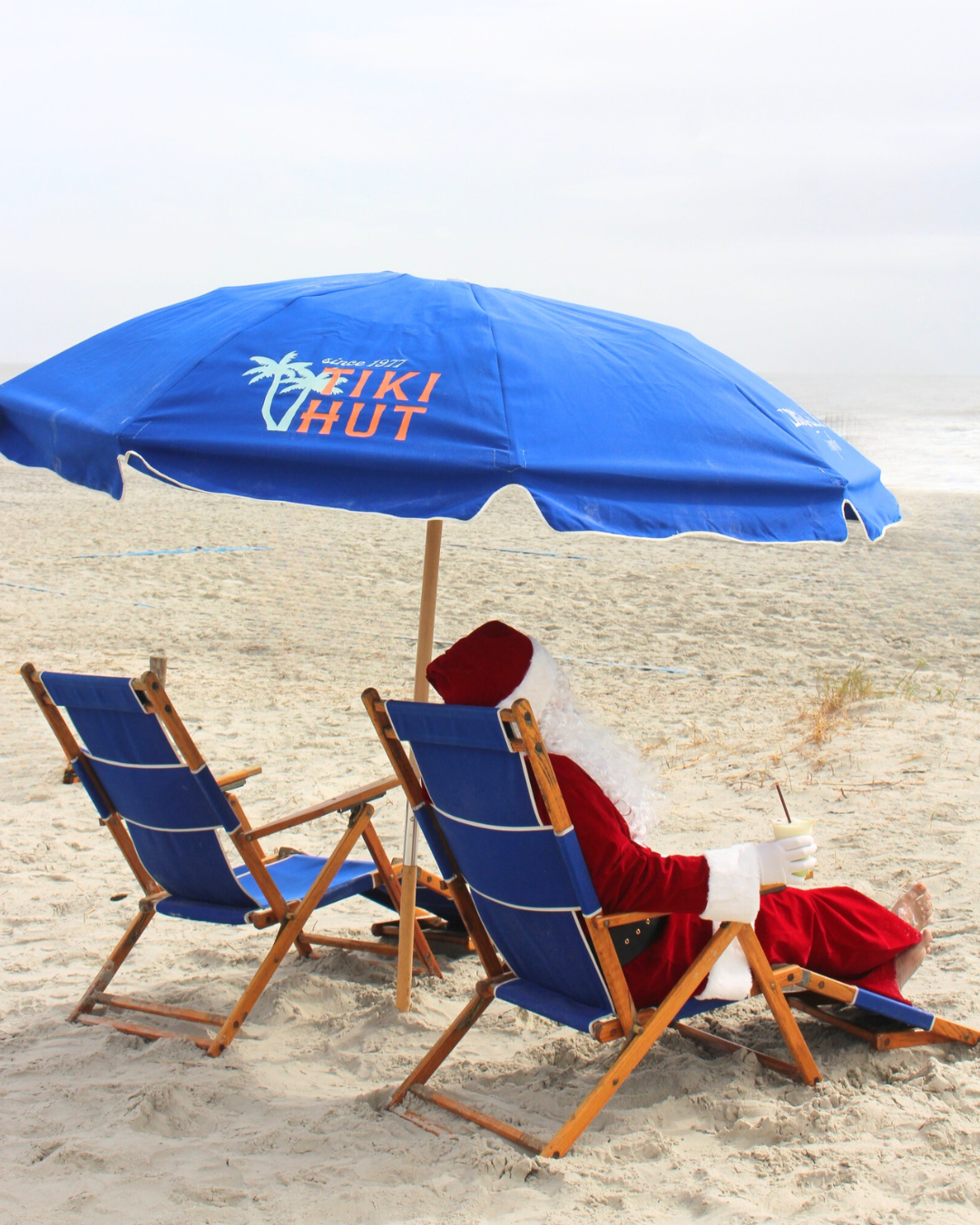 a man in a garment sitting in a chair under an umbrella on a beach