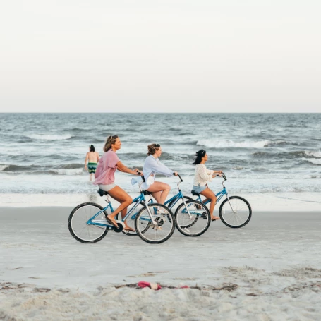 a group of people riding bicycles on a beach