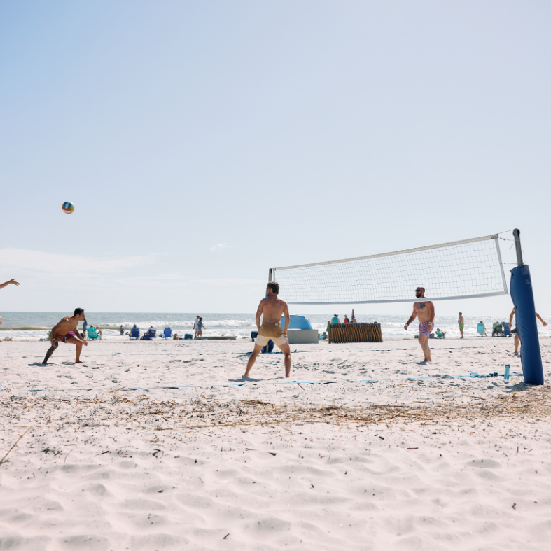 a group of people playing volleyball on a beach